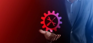 İş adamı araç gereç simgesini araçlarla tutuyor. Dişliler. Hedef odaklı dijital diyagram, grafik arayüzleri, sanal UI ekranı, netwoork bağlantıları kavramı