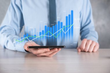 İş adamı elinde pozitif kar artışı olan bir grafik tutuyor. Grafik büyümesi ve grafik artışı işlerinde olumlu göstergeler. Daha kârlı ve büyüyen.