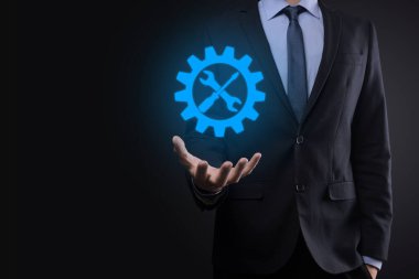 İş adamı araç gereç simgesini araçlarla tutuyor. Dişliler. Hedef odaklı dijital diyagram, grafik arayüzleri, sanal UI ekranı, netwoork bağlantıları kavramı