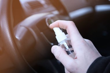Arabanın içini dezenfeksiyon sıvısıyla temizliyorum. Direksiyon ve direksiyon kollarında dezenfeksiyon var. Coronavirus, Covid-19 koruma. İçerideki vihicle dezenfekte ediliyor..