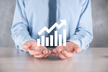 İş adamı elinde pozitif kar artışı olan bir grafik tutuyor. Grafik büyümesi ve grafik artışı işlerinde olumlu göstergeler. Daha kârlı ve büyüyen