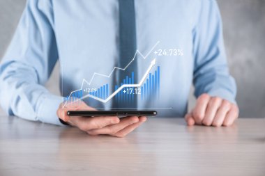 İş adamı elinde pozitif kar artışı olan bir grafik tutuyor. Grafik büyümesi ve grafik artışı işlerinde olumlu göstergeler. Daha kârlı ve büyüyen.