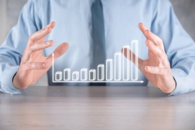 İş adamı elinde pozitif kar artışı olan bir grafik tutuyor. Grafik büyümesi ve grafik artışı işlerinde olumlu göstergeler. Daha kârlı ve büyüyen.