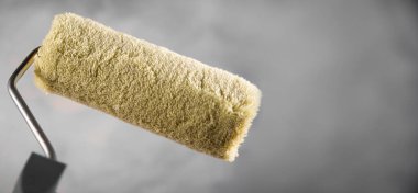 Bulanık beton arka planda boya yapmak için yepyeni bir boya silindiri. Metin için boş alanı kopyala. Reklam afişi