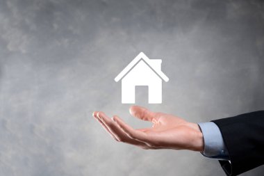 Emlak konsepti, iş adamı ev ikonu tutuyor. Ev elden gidiyor. Emlak sigortası ve güvenlik kavramı. İnsanın jestini ve evin sembolünü koruyorum..