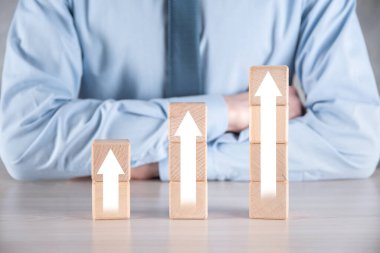 İş geliştirme ve büyüme kavramına. İş adamı, tahta blokları büyüyen grafikler haline getirmeye çalışıyor.