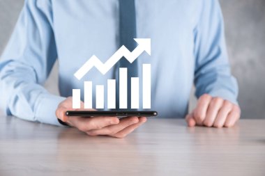 İş adamı elinde pozitif kar artışı olan bir grafik tutuyor. Grafik büyümesi ve grafik artışı işlerinde olumlu göstergeler. Daha kârlı ve büyüyen