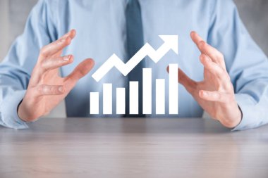İş adamı elinde pozitif kar artışı olan bir grafik tutuyor. Grafik büyümesi ve grafik artışı işlerinde olumlu göstergeler. Daha kârlı ve büyüyen