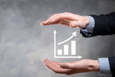 İş adamı elinde pozitif kar artışı olan bir grafik tutuyor. Grafik büyümesi ve grafik artışı işlerinde olumlu göstergeler. Daha kârlı ve büyüyen