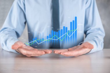 İş adamı elinde pozitif kar artışı olan bir grafik tutuyor. Grafik büyümesi ve grafik artışı işlerinde olumlu göstergeler. Daha kârlı ve büyüyen.