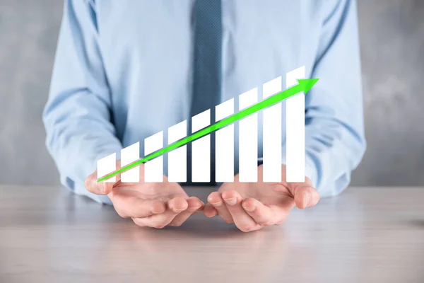 Businessman man holding a graph with positive profits growth. plan graph growth and increase of chart positive indicators in his business.more profitable and growing.