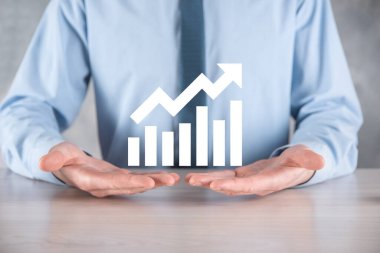 İş adamı elinde pozitif kar artışı olan bir grafik tutuyor. Grafik büyümesi ve grafik artışı işlerinde olumlu göstergeler. Daha kârlı ve büyüyen