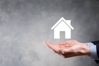 Emlak konsepti, iş adamı ev ikonu tutuyor. Ev elden gidiyor. Emlak sigortası ve güvenlik kavramı. İnsanın jestini ve evin sembolünü koruyorum..