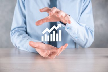 İş adamı elinde pozitif kar artışı olan bir grafik tutuyor. Grafik büyümesi ve grafik artışı işlerinde olumlu göstergeler. Daha kârlı ve büyüyen