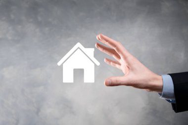 Emlak konsepti, iş adamı ev ikonu tutuyor. Ev elden gidiyor. Emlak sigortası ve güvenlik kavramı. İnsanın jestini ve evin sembolünü koruyorum..