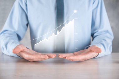 İş adamı elinde pozitif kar artışı olan bir grafik tutuyor. Grafik büyümesi ve grafik artışı işlerinde olumlu göstergeler. Daha kârlı ve büyüyen.
