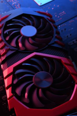 Bilgisayar oyunu grafikleri kartı, devre kartında iki soğutucu olan video oyunu, anakart geçmişi. Yakın plan. Kırmızı-mavi ışıkla.