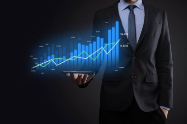 Holografik grafikler ve borsa istatistikleri tutan işadamı kâr elde ediyor. Büyüme planlama ve iş stratejisi kavramı. İyi ekonomi formunun dijital ekran görüntüsü