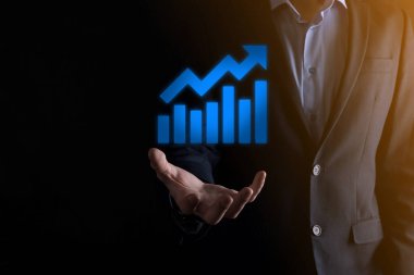 İş adamı elinde pozitif kar artışı olan bir grafik tutuyor. Grafik büyümesi ve grafik artışı işlerinde olumlu göstergeler. Daha kârlı ve büyüyen