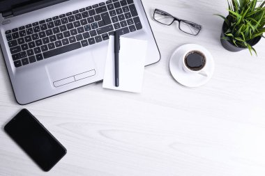 Bilgisayarlı masa masası, akıllı telefon, bir fincan kahve ve malzeme, ahşap arka planda. Kopyalama alanı olan üst görünüm, düz yatay