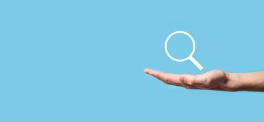 Erkek el büyüteç tutuyor, mavi arkaplanda arama simgesi var. Konsept arama motoru optimizasyonu, müşteri desteği. İnternet Veri Bilgilerine göz atılıyor. Ağ Konsepti