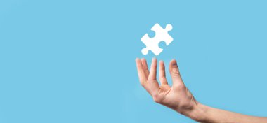 Mavi arka planda erkek eli yapboz simgesi var. İki şirketin birleşmesini veya ortak girişim, ortaklık, birleşme ve satın alma kavramını temsil eden parçalar