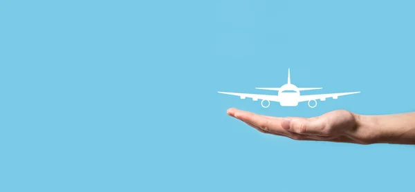 Male hand holding plane airplane icon on blue background. Banner.nline ticket purchase.Travel icons about travel planning, transportation, hotel, flight and passport.Flight ticket booking concept