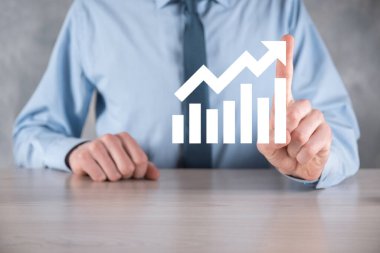 İş adamı elinde pozitif kar artışı olan bir grafik tutuyor. Grafik büyümesi ve grafik artışı işlerinde olumlu göstergeler. Daha kârlı ve büyüyen