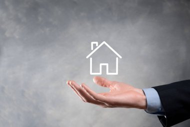 Emlak konsepti, iş adamı ev ikonu tutuyor. Ev elden gidiyor. Emlak sigortası ve güvenlik kavramı. İnsanın jestini ve evin sembolünü koruyorum..