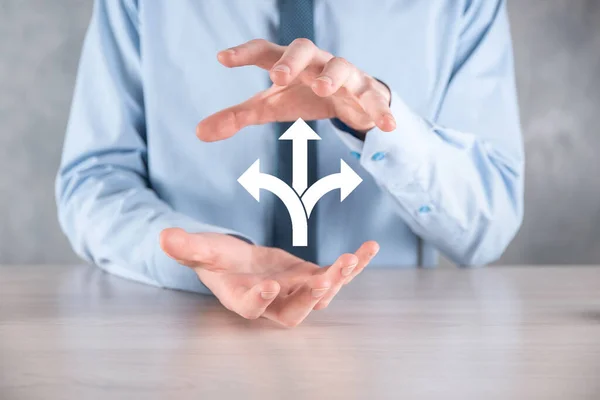 Businessman in a suit holds a sign showing three directions. in doubt, having to choose between three different choices indicated by arrows pointing in opposite direction concept. three ways to choose.