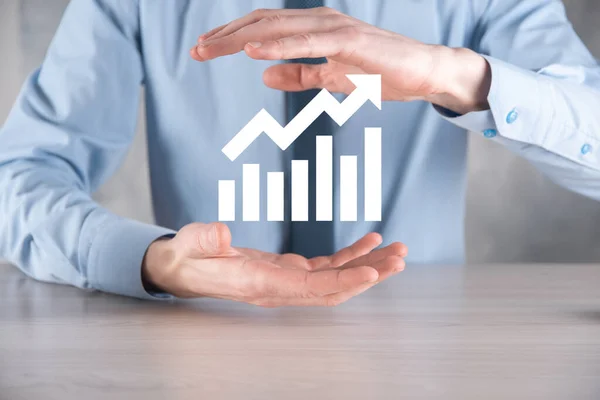 Businessman man holding a graph with positive profits growth. plan graph growth and increase of chart positive indicators in his business.more profitable and growing