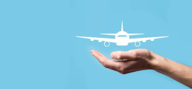 Erkek el, mavi arka planda uçak ikonunu tutuyor. Banner. Nline bilet alımı. Seyahat planlama, ulaşım, otel, uçuş ve pasaport ikonları.