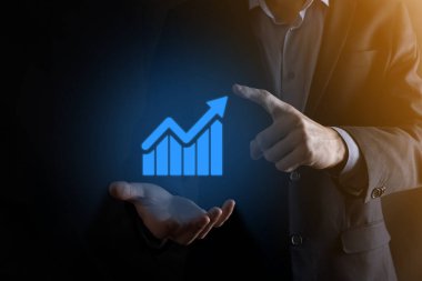 İş adamı elinde pozitif kar artışı olan bir grafik tutuyor. Grafik büyümesi ve grafik artışı işlerinde olumlu göstergeler. Daha kârlı ve büyüyen