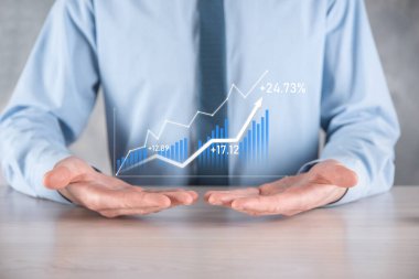 İş adamı elinde pozitif kar artışı olan bir grafik tutuyor. Grafik büyümesi ve grafik artışı işlerinde olumlu göstergeler. Daha kârlı ve büyüyen.