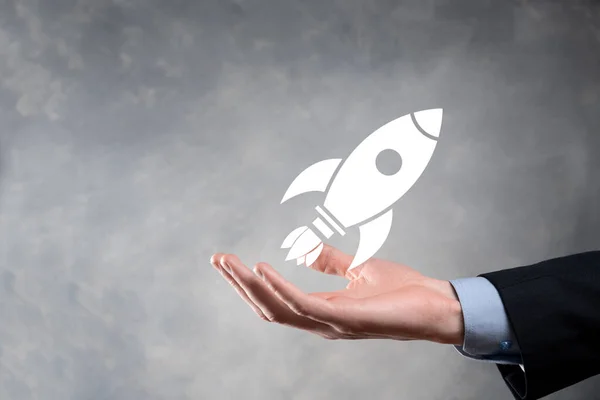 Startup business concept, Businessman holding tablet and icon rocket is launching and soar flying out from screen with network connection on dark background