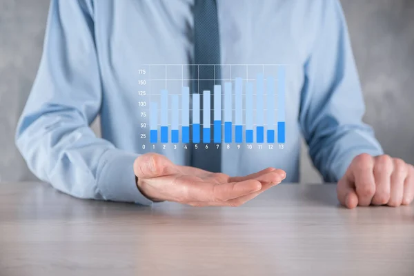Businessman man holding a graph with positive profits growth. plan graph growth and increase of chart positive indicators in his business.more profitable and growing.