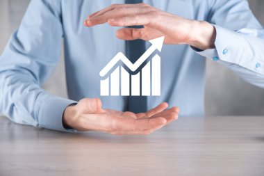 İş adamı elinde pozitif kar artışı olan bir grafik tutuyor. Grafik büyümesi ve grafik artışı işlerinde olumlu göstergeler. Daha kârlı ve büyüyen