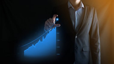 Holografik grafikler ve borsa istatistikleri tutan işadamı kâr elde ediyor. Büyüme planlama ve iş stratejisi kavramı. İyi ekonomi formunun dijital ekran görüntüsü
