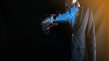 İş adamı holografik grafikler ve borsa istatistikleri tutuyor ve gösteriyor. Büyüme planlama ve iş stratejisi kavramı. İyi ekonomi formunun dijital ekran görüntüsü
