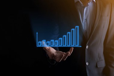 Holografik grafikler ve borsa istatistikleri tutan işadamı kâr elde ediyor. Büyüme planlama ve iş stratejisi kavramı. İyi ekonomi formunun dijital ekran görüntüsü