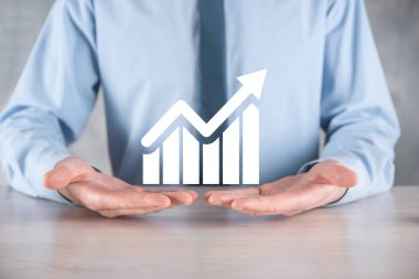 İş adamı elinde pozitif kar artışı olan bir grafik tutuyor. Grafik büyümesi ve grafik artışı işlerinde olumlu göstergeler. Daha kârlı ve büyüyen