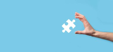 Mavi arka planda erkek eli yapboz simgesi var. İki şirketin birleşmesini veya ortak girişim, ortaklık, birleşme ve satın alma kavramını temsil eden parçalar