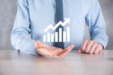 İş adamı elinde pozitif kar artışı olan bir grafik tutuyor. Grafik büyümesi ve grafik artışı işlerinde olumlu göstergeler. Daha kârlı ve büyüyen