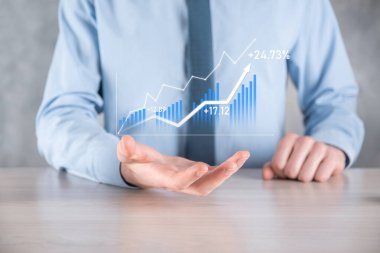 İş adamı elinde pozitif kar artışı olan bir grafik tutuyor. Grafik büyümesi ve grafik artışı işlerinde olumlu göstergeler. Daha kârlı ve büyüyen.