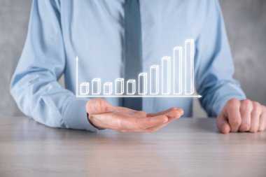 İş adamı elinde pozitif kar artışı olan bir grafik tutuyor. Grafik büyümesi ve grafik artışı işlerinde olumlu göstergeler. Daha kârlı ve büyüyen.