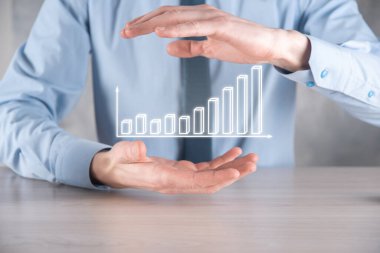 İş adamı elinde pozitif kar artışı olan bir grafik tutuyor. Grafik büyümesi ve grafik artışı işlerinde olumlu göstergeler. Daha kârlı ve büyüyen.