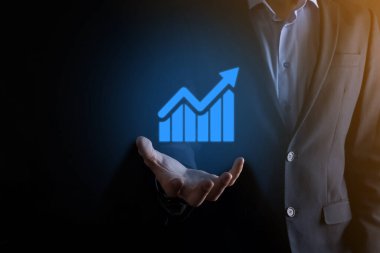 İş adamı elinde pozitif kar artışı olan bir grafik tutuyor. Grafik büyümesi ve grafik artışı işlerinde olumlu göstergeler. Daha kârlı ve büyüyen