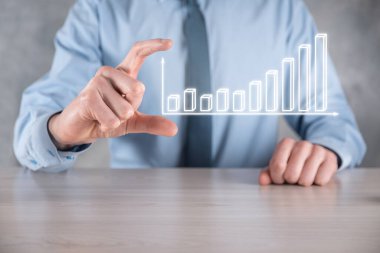 İş adamı elinde pozitif kar artışı olan bir grafik tutuyor. Grafik büyümesi ve grafik artışı işlerinde olumlu göstergeler. Daha kârlı ve büyüyen.