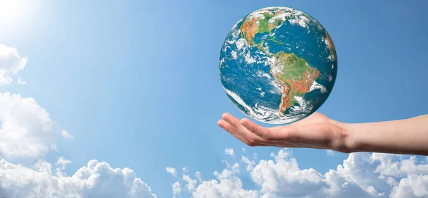 Hands holding a planet, earth on a background of nature blue sky with beautiful white clouds and sunlight.Sustain earth concept. Elements of this image furnished by NASA.