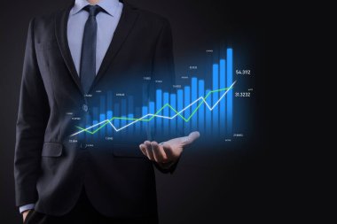 Holografik grafikler ve borsa istatistikleri tutan işadamı kâr elde ediyor. Büyüme planlama ve iş stratejisi kavramı. İyi ekonomi formunun dijital ekran görüntüsü